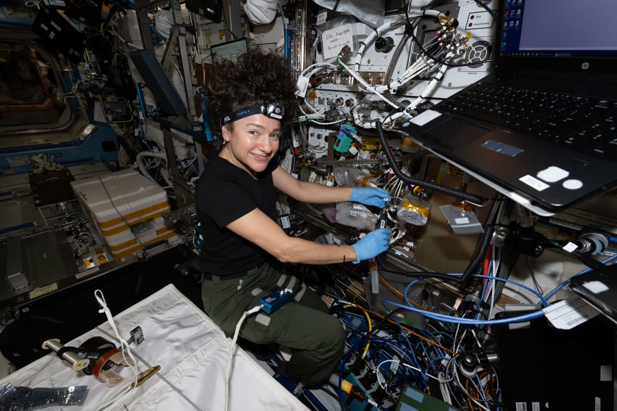 Astronaut inspecting fiber optic cables inside NASA's Cold Atom Lab on International Space Station