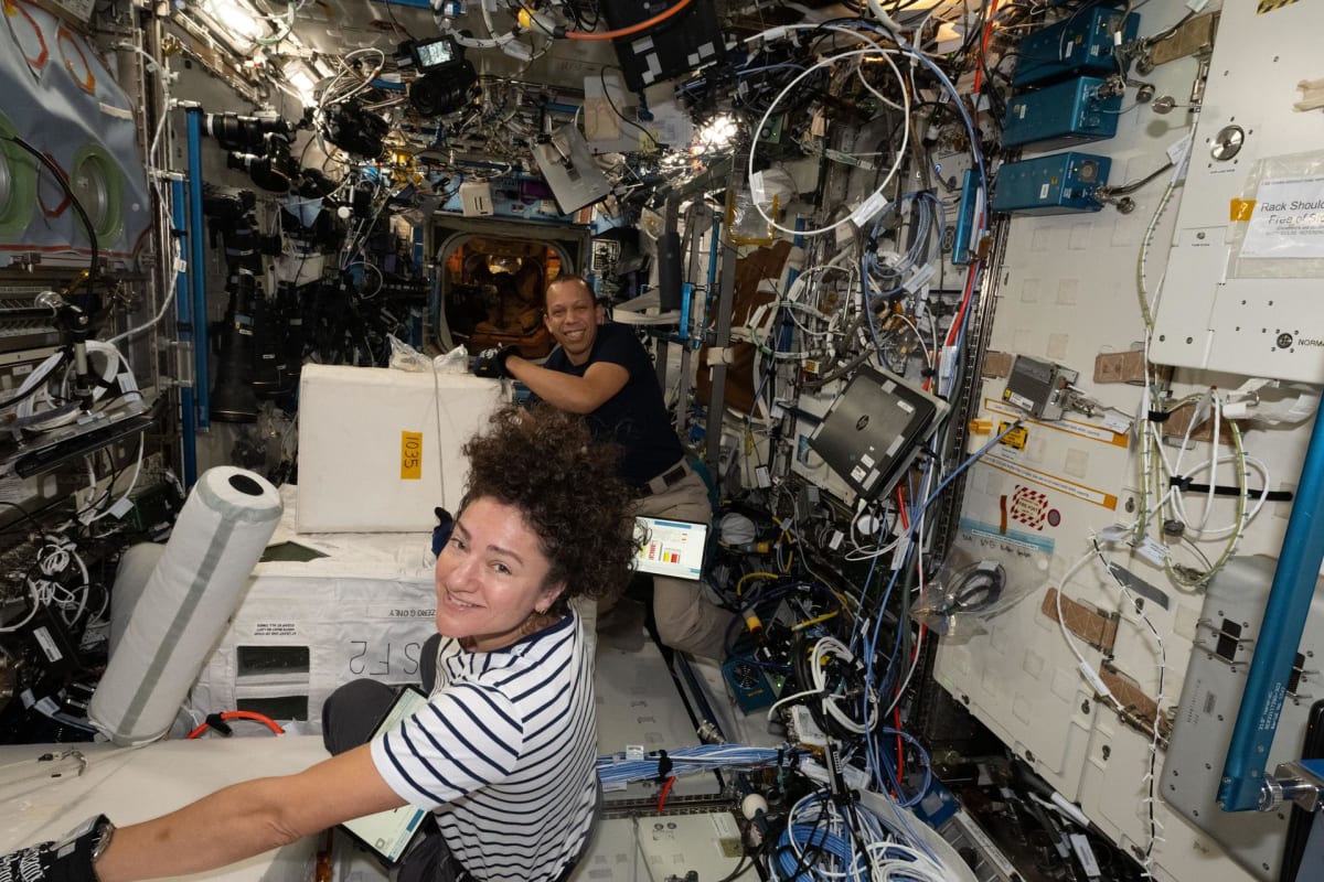 NASA astronauts Jessica Meir and Chris Williams handle frozen research samples aboard the International Space Station