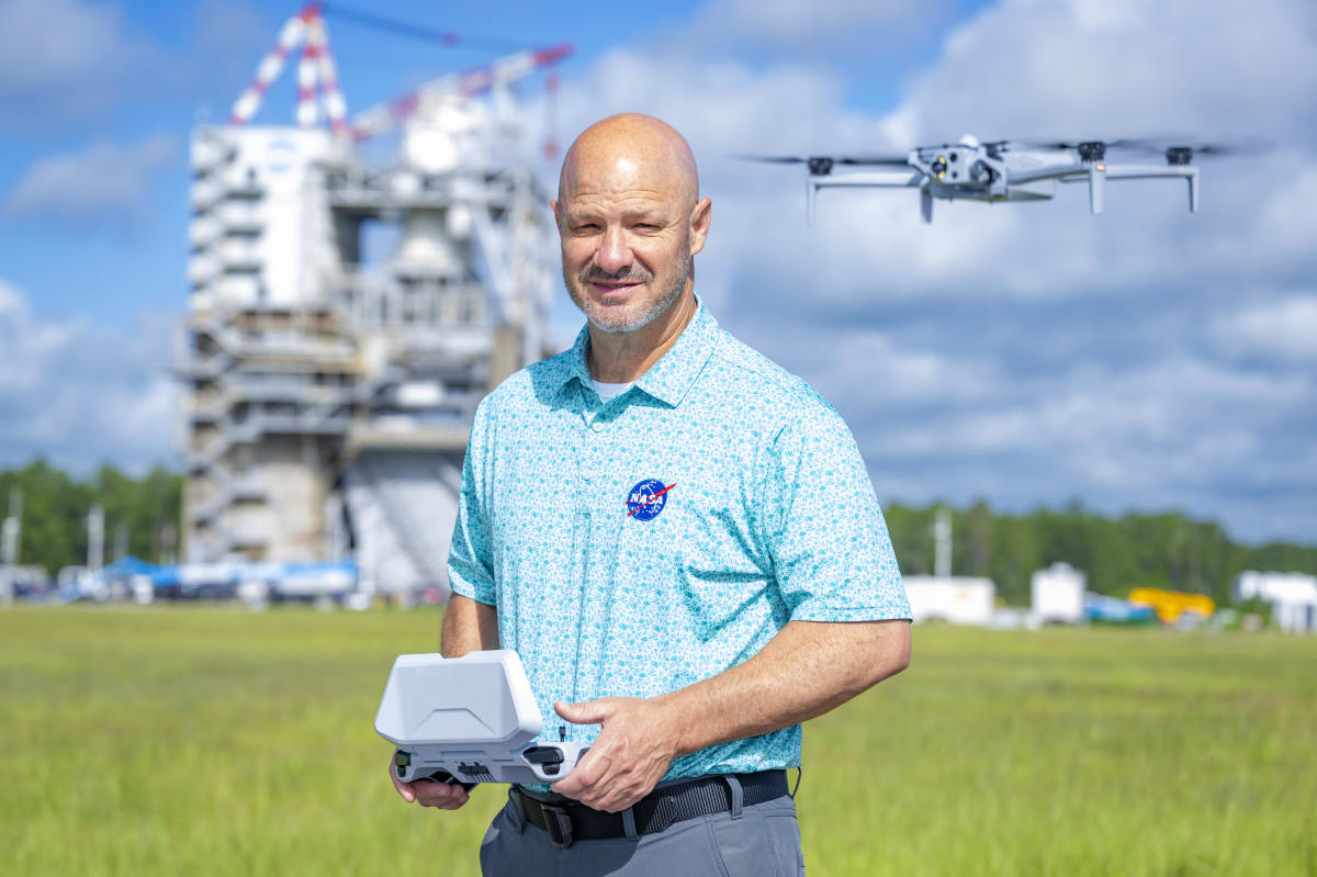 NASA range operations manager Jason Peterson stands beside the Artemis II Orion spacecraft aboard Navy ship