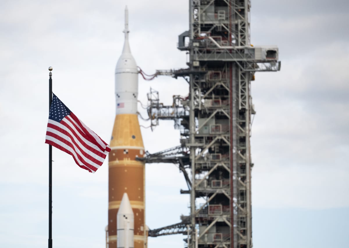 American flag waves in front of NASA's Space Launch System rocket at Kennedy Space Center