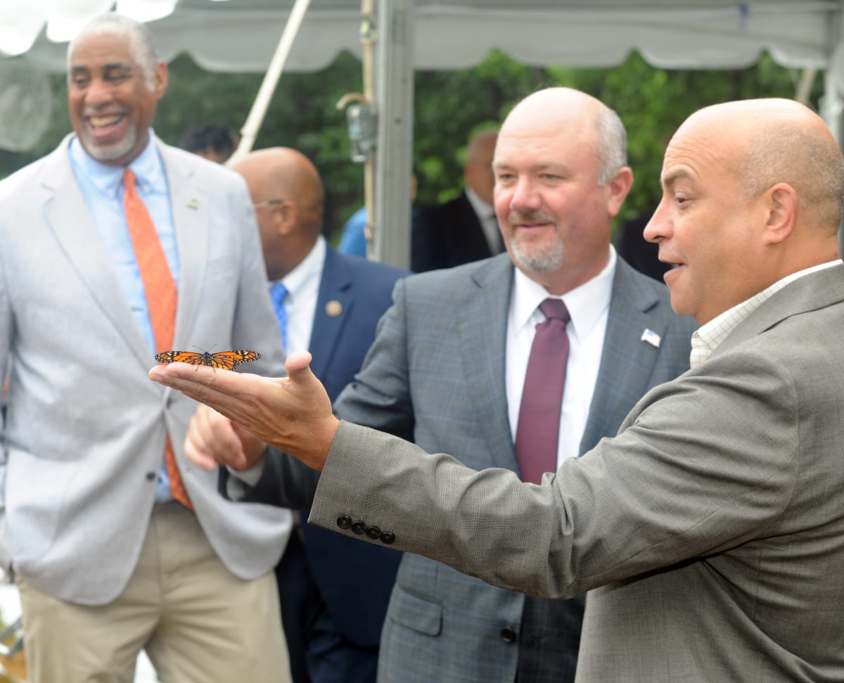 Officials hold pennant at forested Area 400 during NASA land transfer ceremony in Maryland