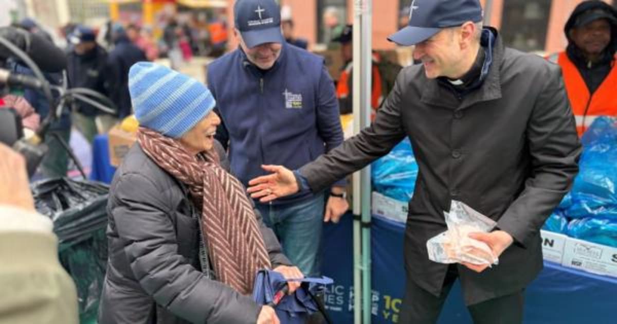 Archbishop Ronald Hicks hands food packages to families waiting in line at Manhattan distribution event