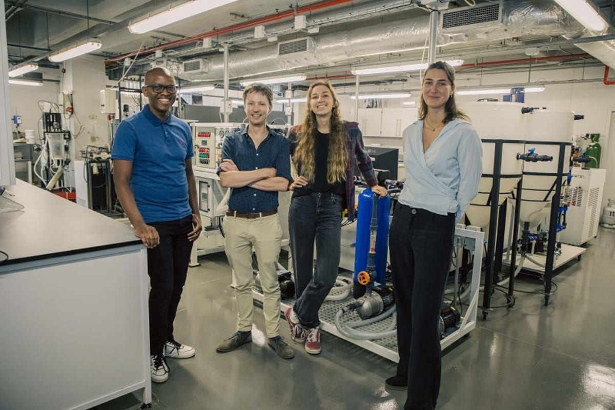 Four PeeCycling team members standing together holding bottles of sustainable fertilizer made from urine
