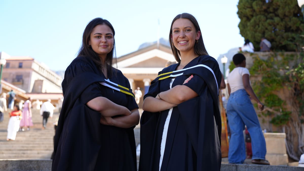 Three women graduates holding expandable school shoe prototype with smart tracking technology