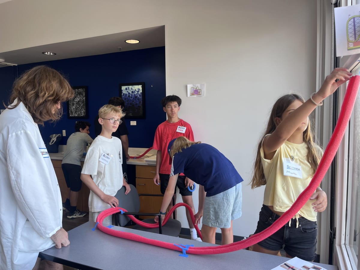 Middle school students building marble rollercoasters with tape and pool noodles in UCSB classroom