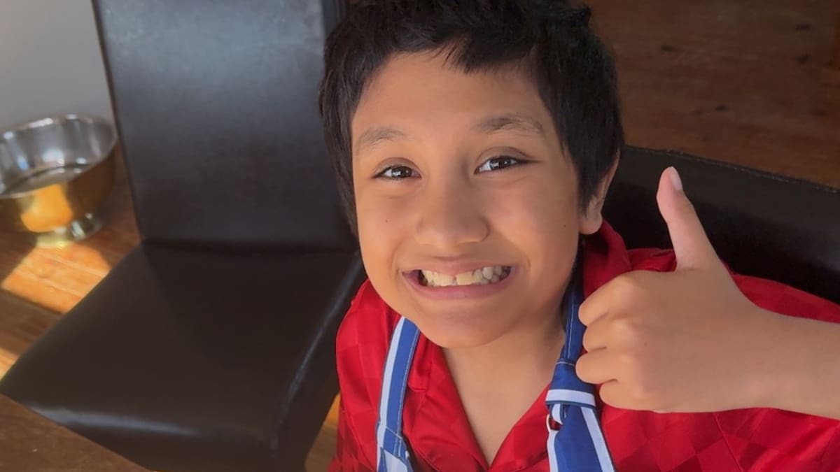 Young boy Legacy Haenga smiling while baking treats in kitchen for hospital fundraiser