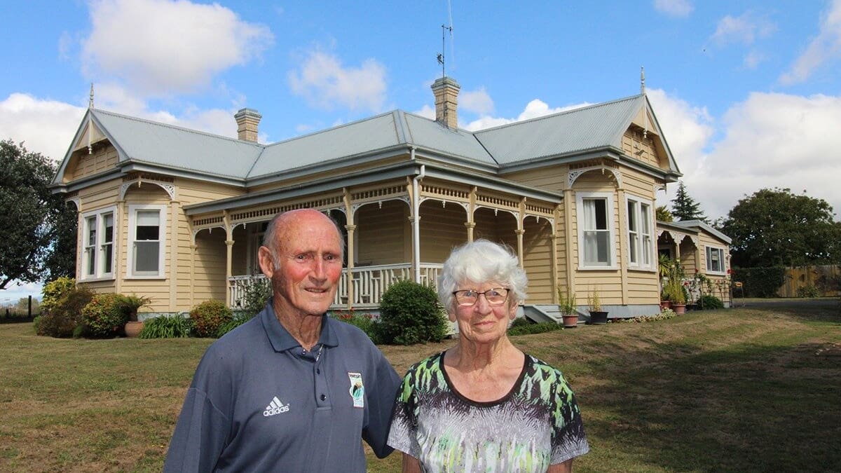 Historic white Edwardian villa homestead with wraparound verandah and decorative fretwork on New Zealand dairy farm