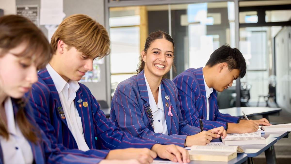 Diverse group of high school graduates in academic gowns celebrating at graduation ceremony in Auckland