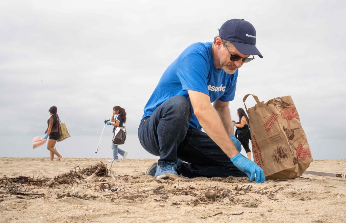 ** Volunteers with trash pickers searching sand for pollution at Huntington State Beach cleanup event