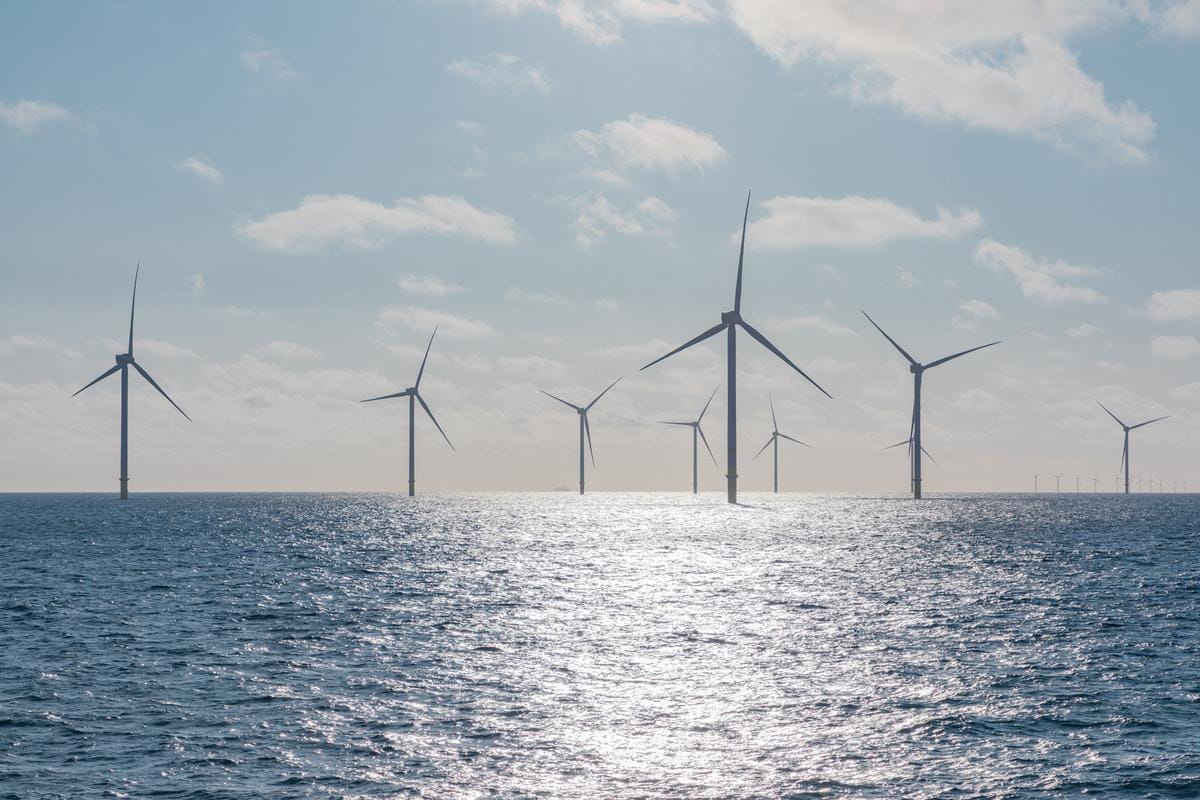 Offshore wind turbines standing in blue ocean waters generating renewable electricity