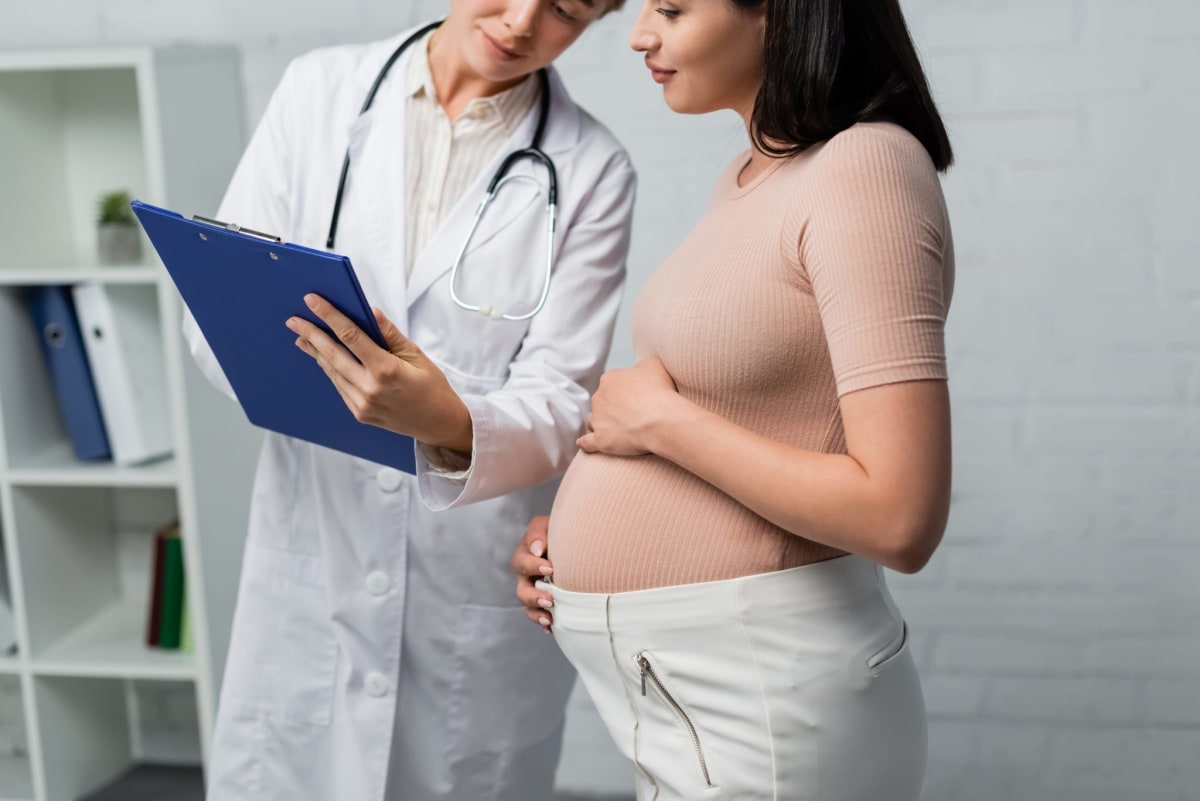 Pregnant woman holding her belly in warm sunlight, celebrating motherhood and health