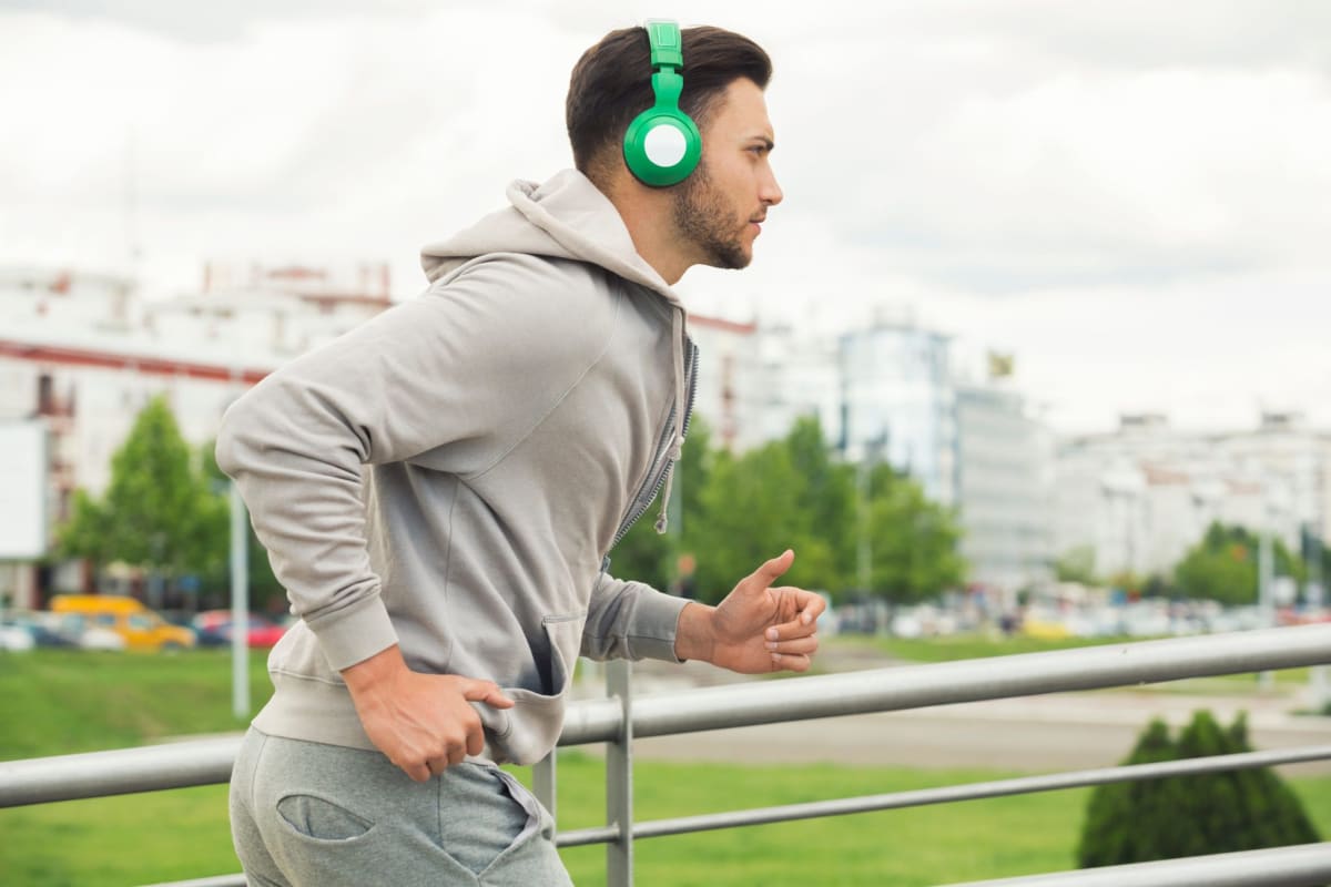 Person cycling on stationary bike wearing headphones with focused expression during intense workout