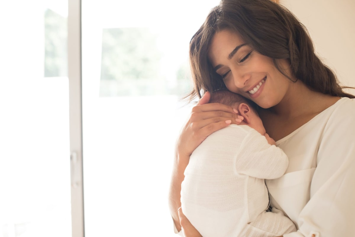 Chilean mother holding infant while working at computer in home office setting