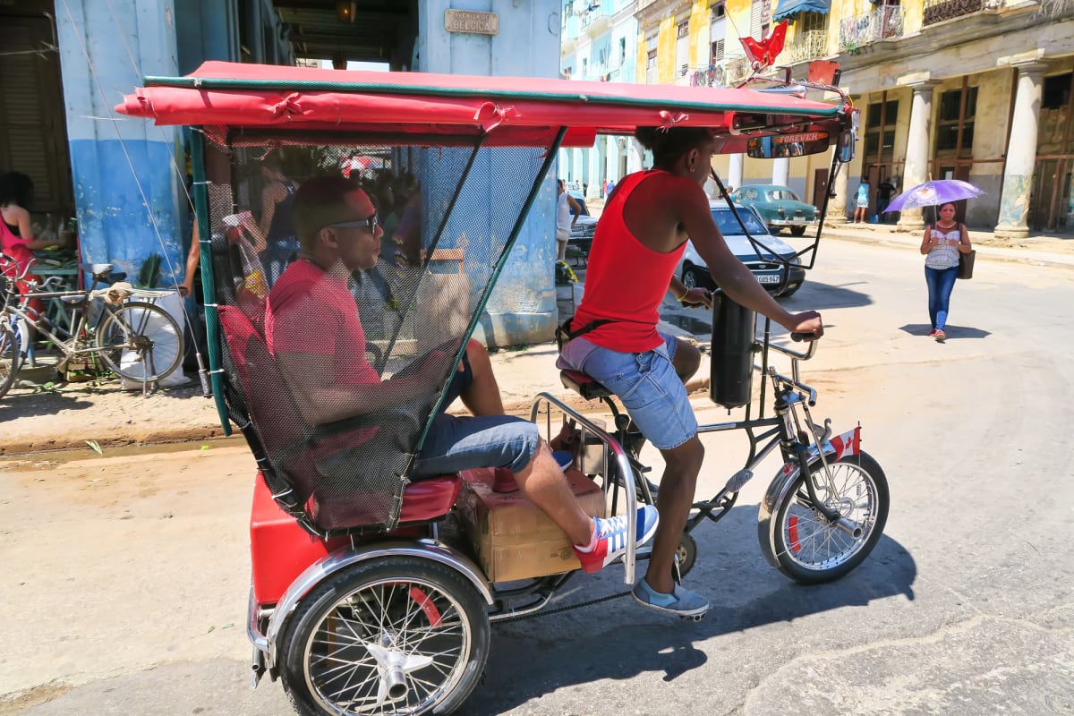 Electric tricycle with solar panel mounted on passenger awning driving through Havana street
