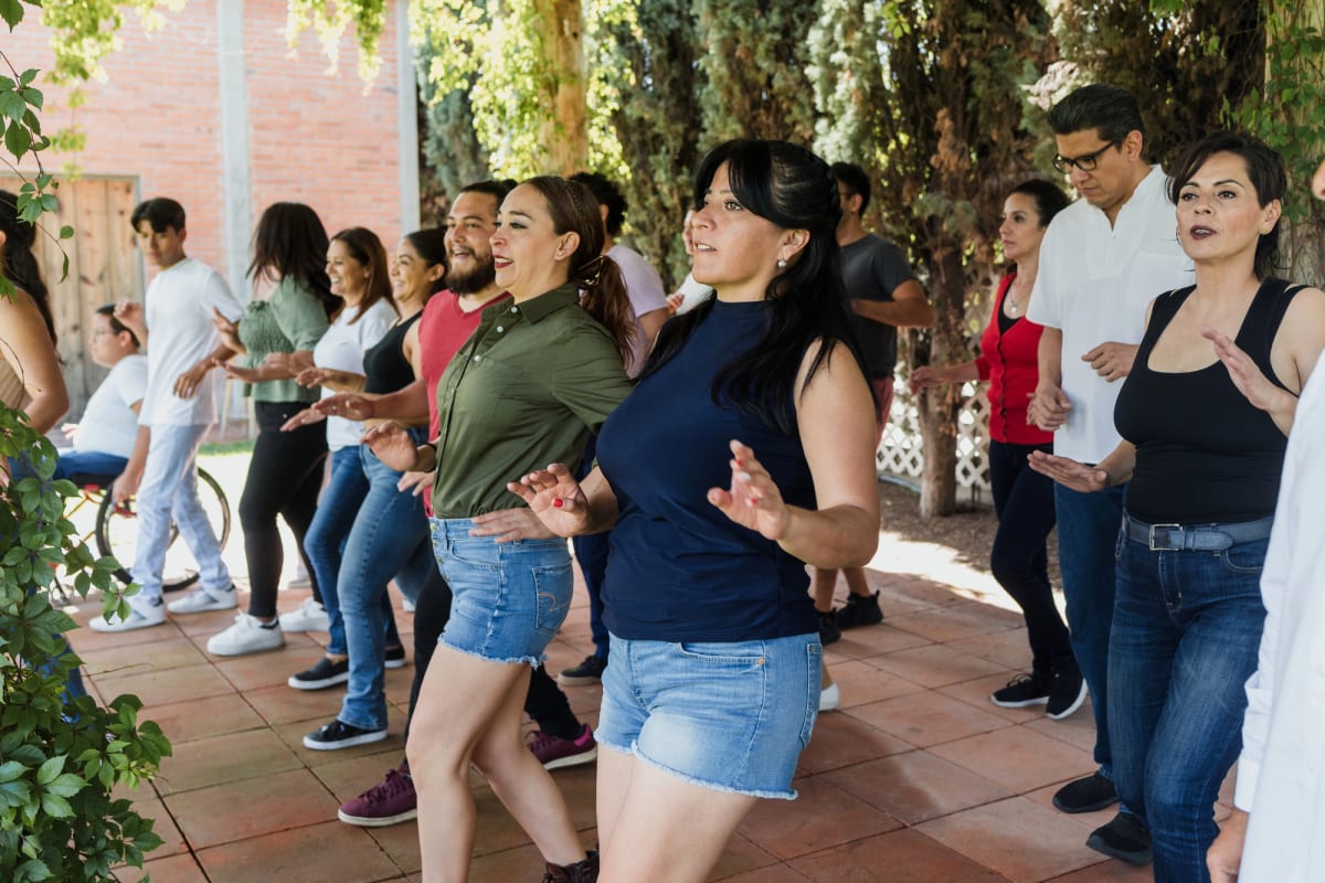 Young adults smile while learning salsa dance steps together in a bright community studio