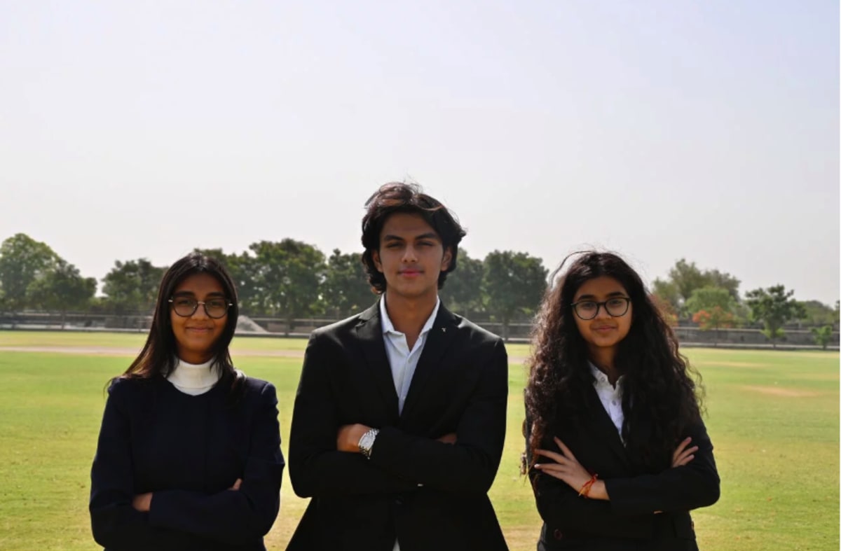 Teenage students presenting environmental innovation prototypes including biodegradable plastic and water filtration systems