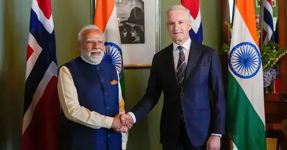 Solar panels and wind turbines against blue sky representing India-Norway clean energy partnership