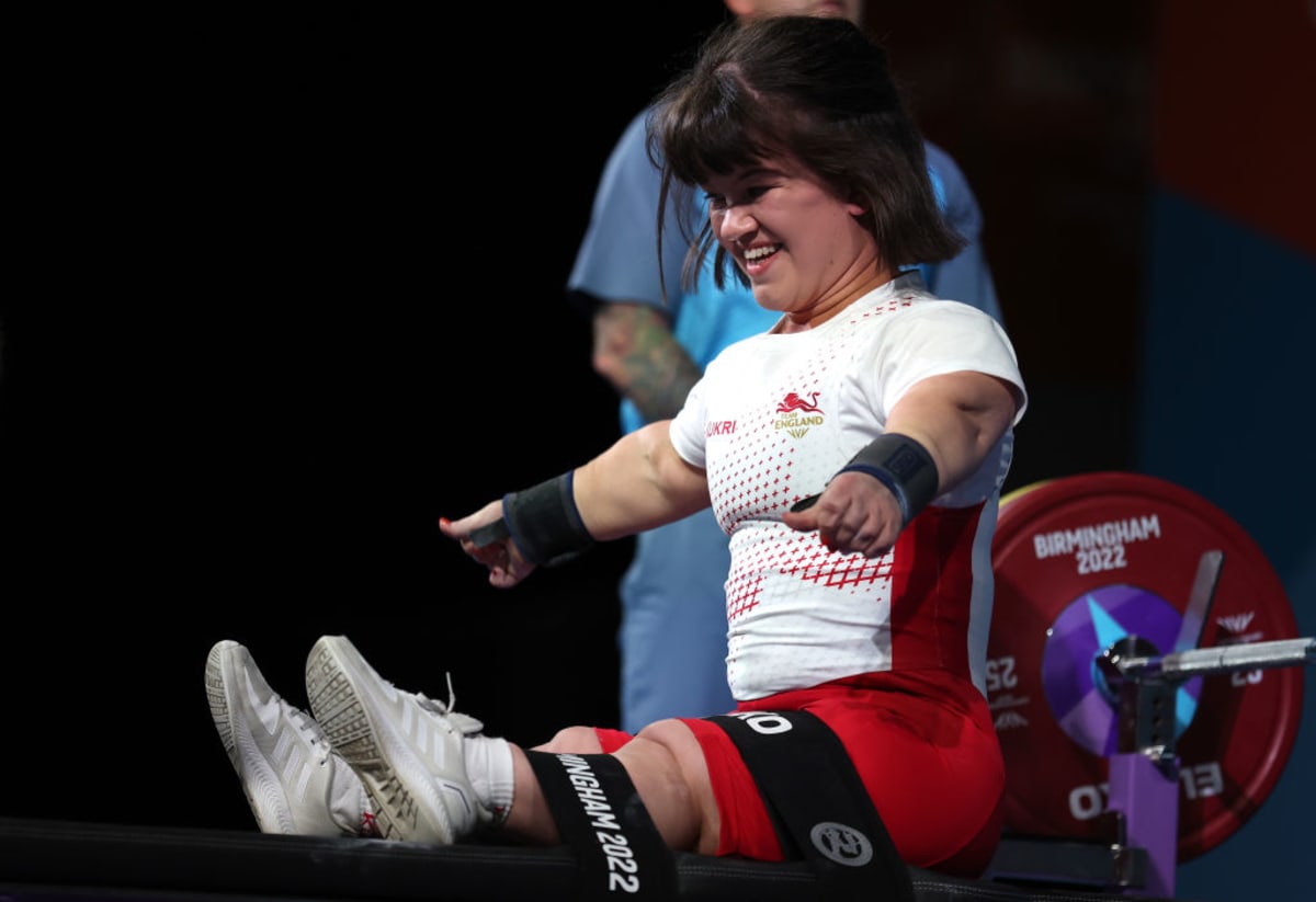 ** Para powerlifter Olivia Broome competing in wheelchair lifting heavy barbell overhead at Paralympic competition