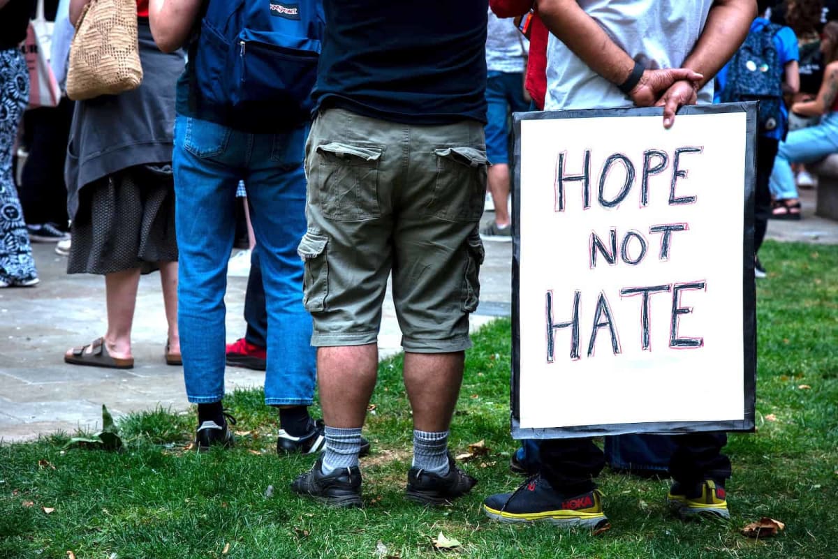 Large crowd of diverse protesters marching through London streets with anti-racism signs and banners