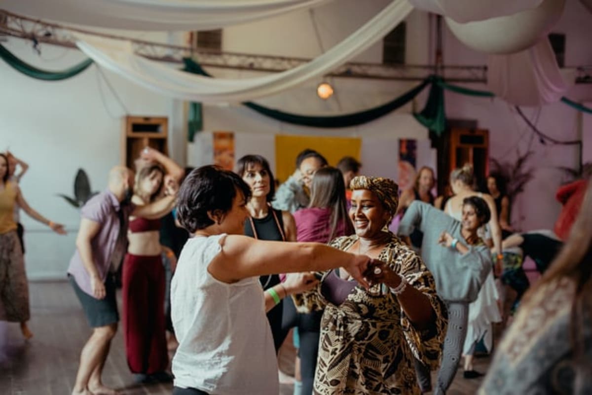 Diverse group of people dancing freely in bright community space during daytime event