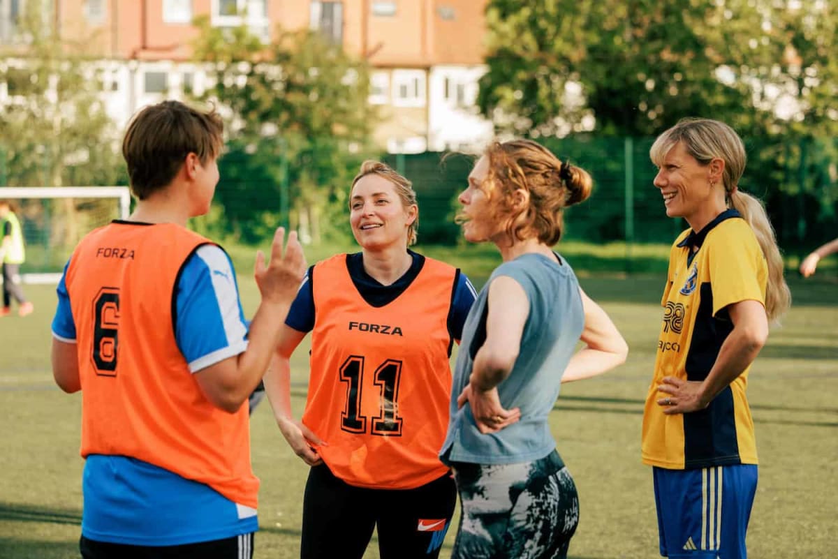 Diverse group of women playing football on floodlit pitch in south London