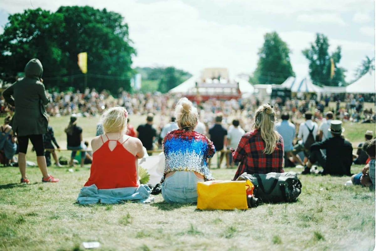 Young festival attendees sorting colorful plastic waste at outdoor recycling workshop tables in London park