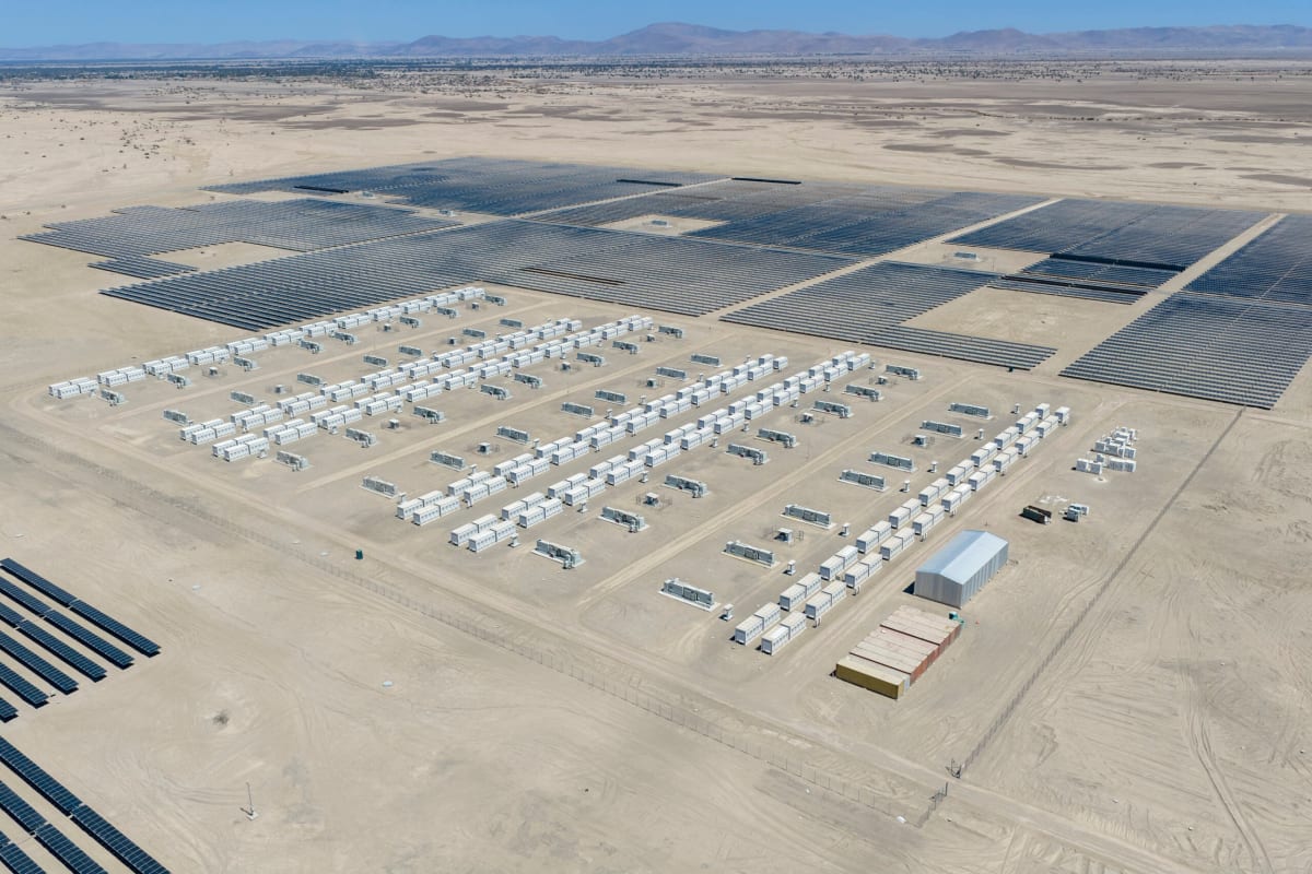 Large solar panel array in Chilean desert with battery storage facility under blue sky