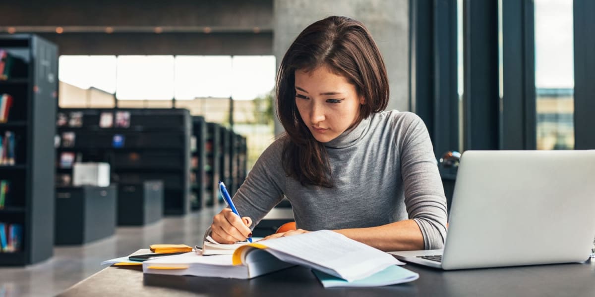 College student studying at desk with books, focused on long-term academic goals