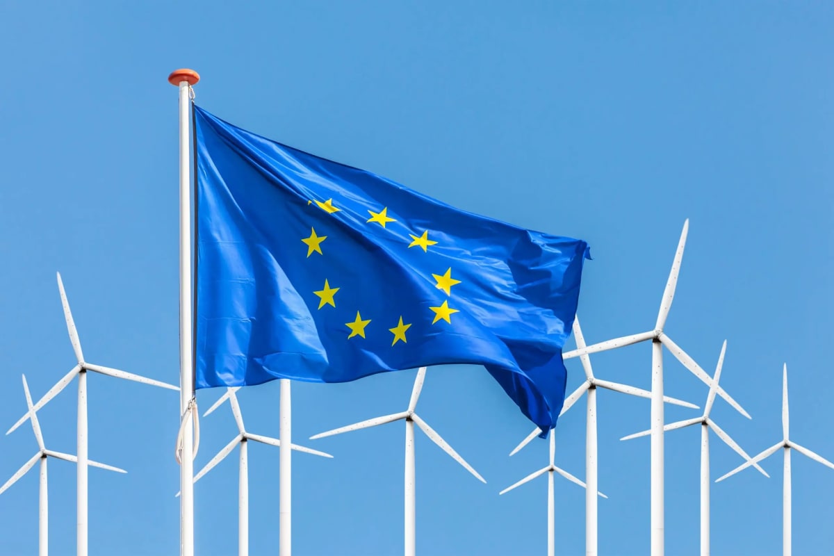 Solar panels and wind turbines stretching across sunny Mediterranean coastal landscape with modern power lines