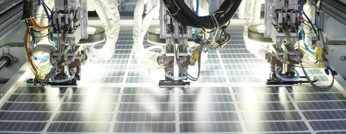 Solar panel manufacturing facility with workers assembling photovoltaic cells in modern American factory