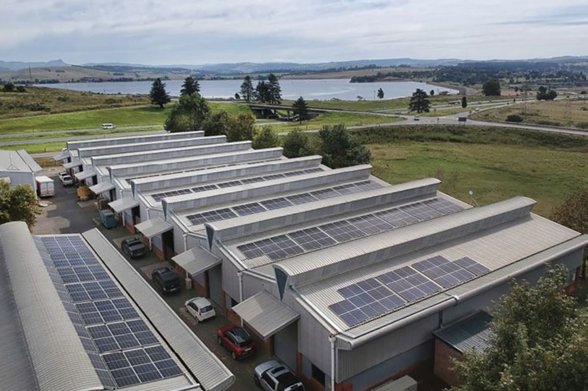 Solar panels installed on commercial building rooftop with African cityscape in background
