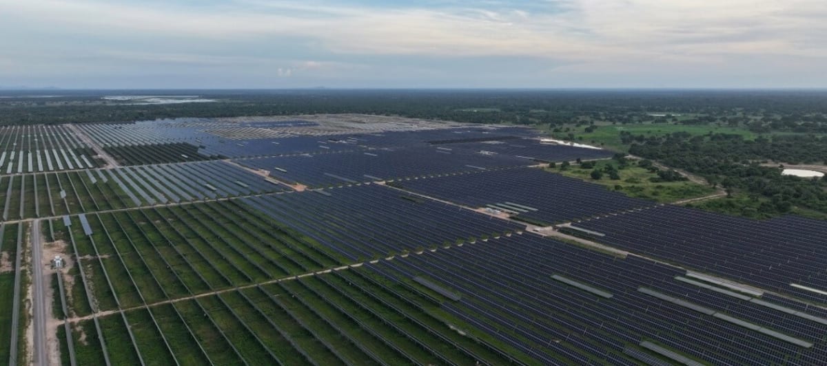 Solar panel arrays stretching across Colombian landscape under bright blue sky generating clean renewable energy