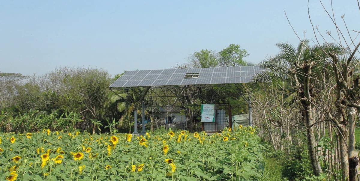 Solar panels installed across rooftop of industrial building in Bangladesh under blue sky