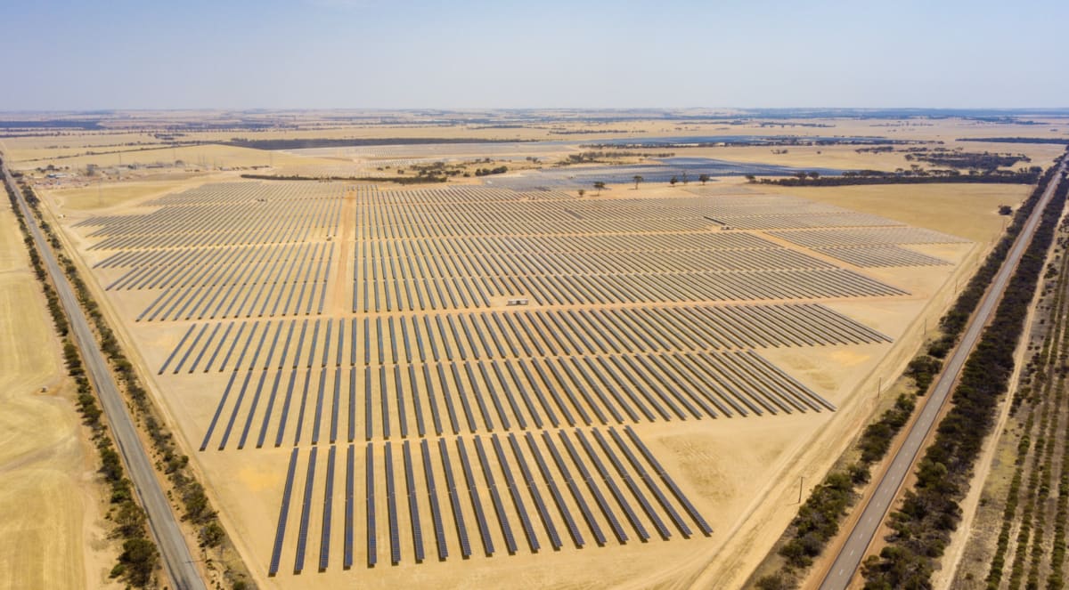 Rows of solar panels stretching across Australian landscape under bright blue sky