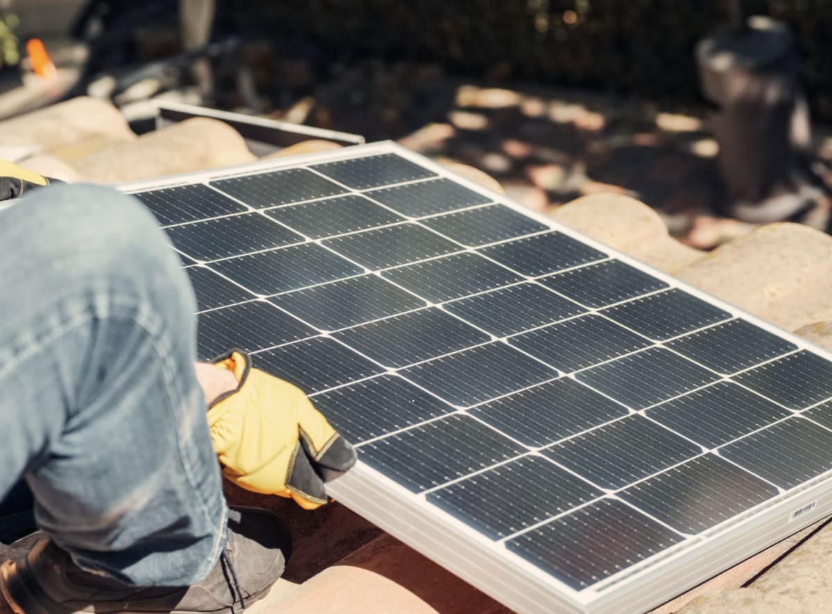 Solar panels installed on residential rooftop with battery storage system on sunny day