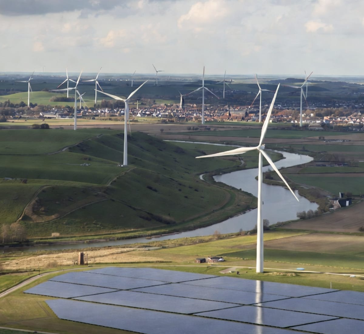 Solar panels and wind turbines generating renewable electricity across Dutch countryside landscape