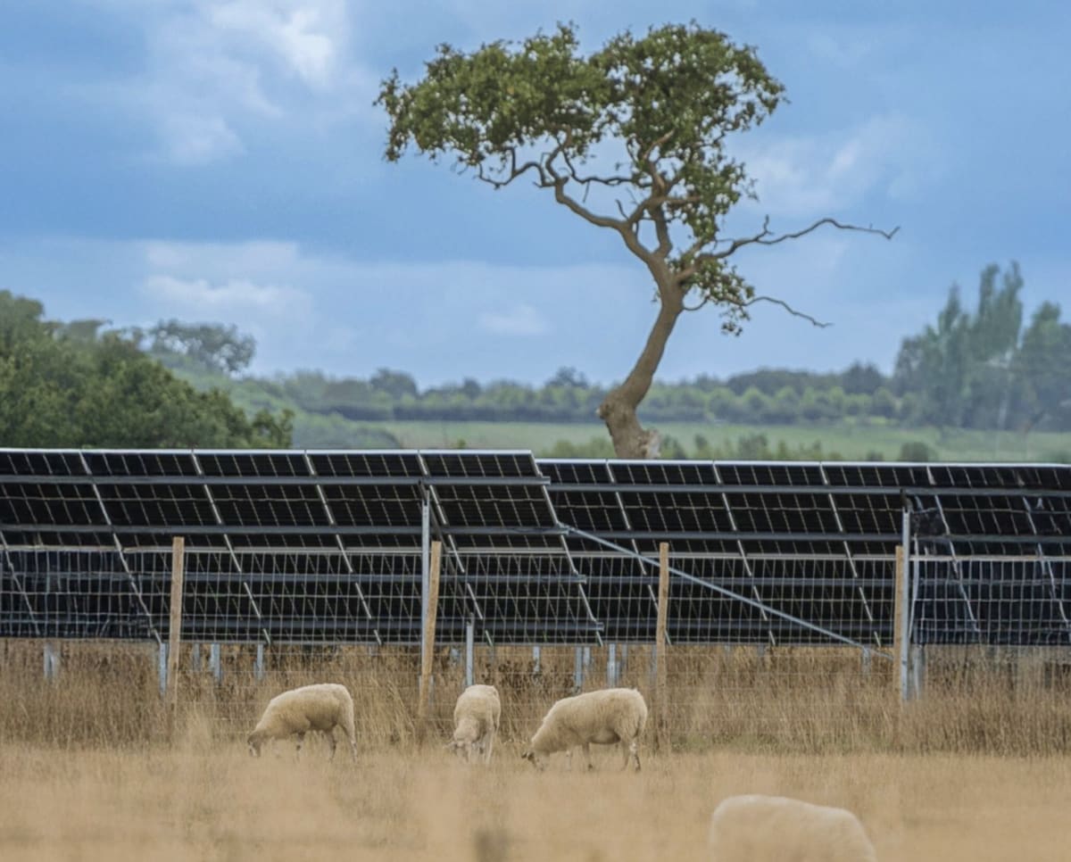 Solar panels spread across green British countryside with battery storage facility nearby