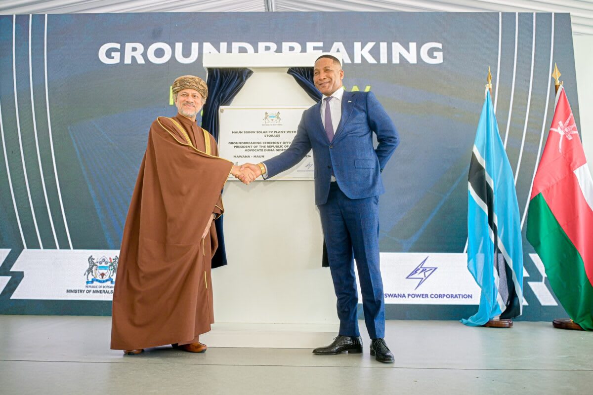 Solar panels stretching across Botswana landscape with construction equipment at groundbreaking ceremony