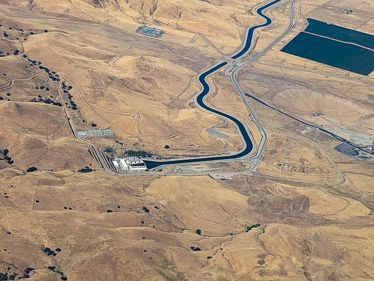 Rows of solar panels stretching across California landscape near Tehachapi Mountains with pumping facility