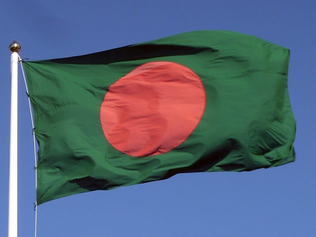 Solar panels installed across Bangladesh landscape with power transmission lines under blue sky