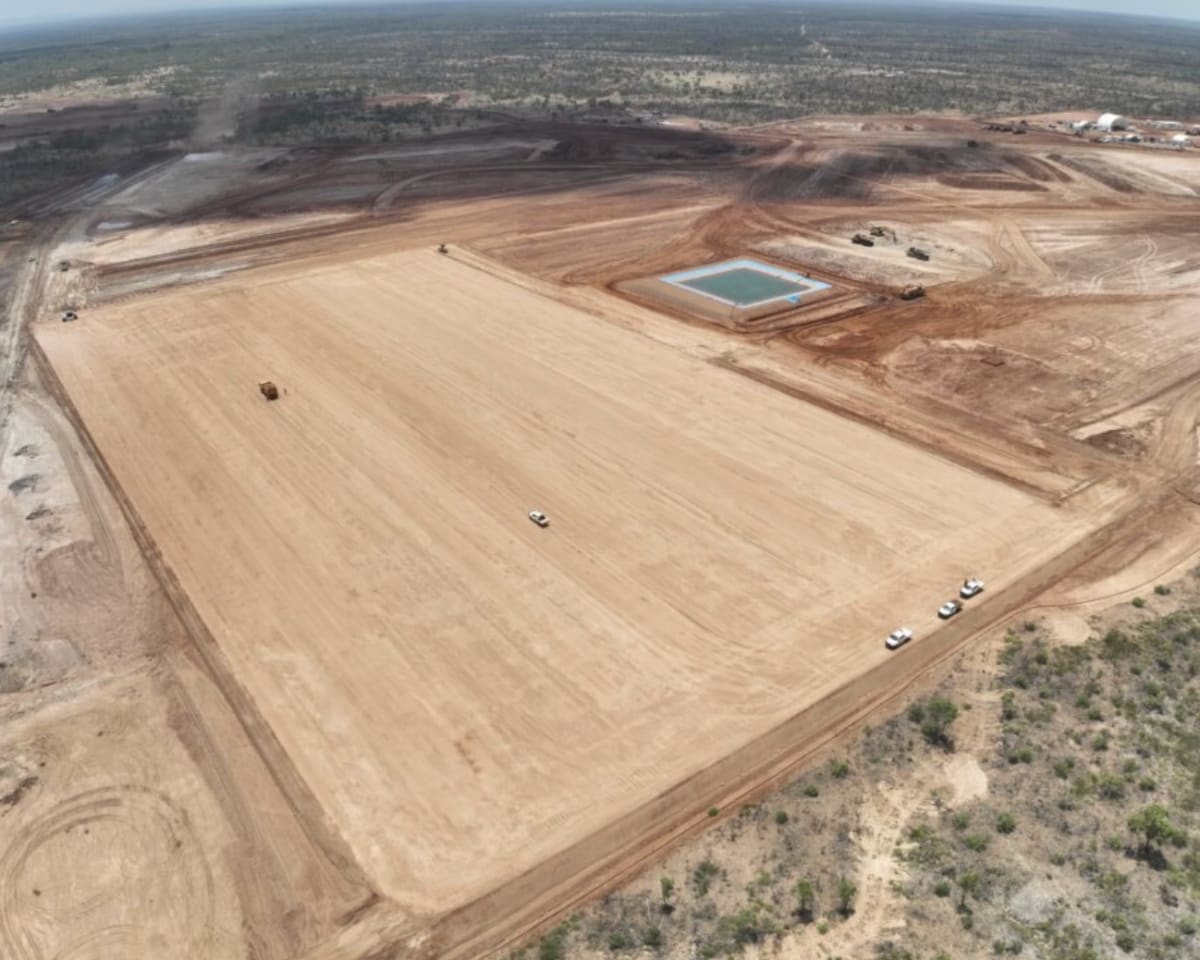 Large solar panel array in remote Australian outback with mining equipment in background