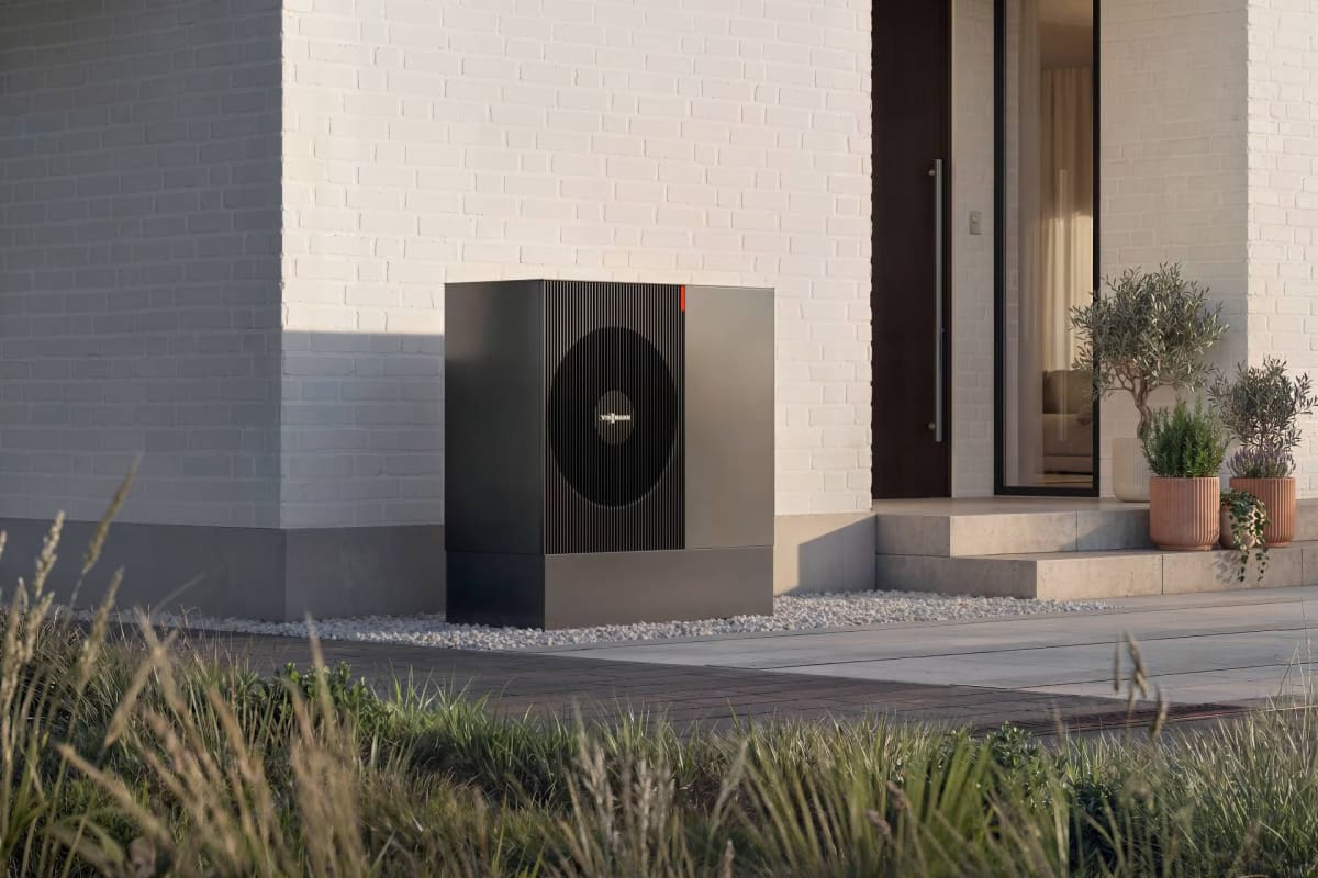 Modern white residential heat pump unit installed outside a European family home