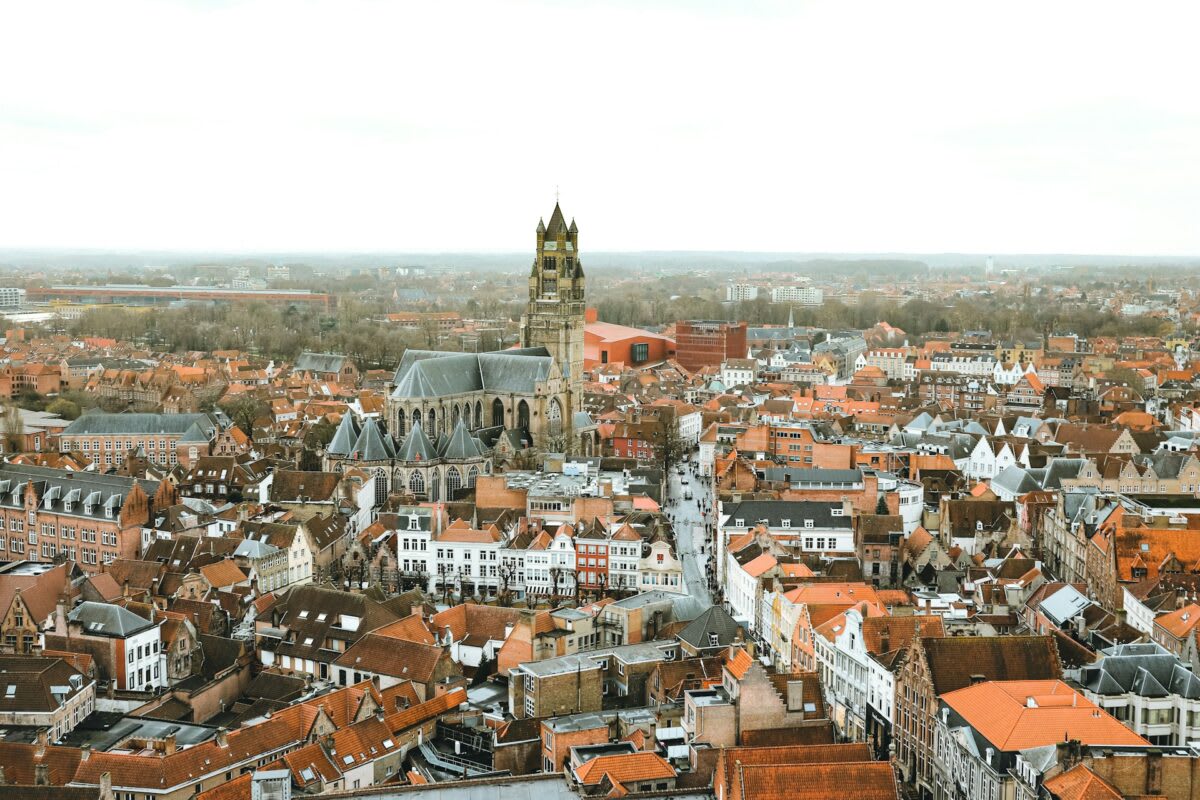 Solar panels covering large commercial rooftop in historic Bruges, Belgium under clear blue sky