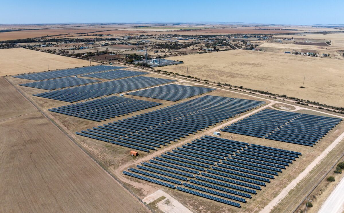 Solar panels and wind turbines stretching across Australian landscape under bright blue sky