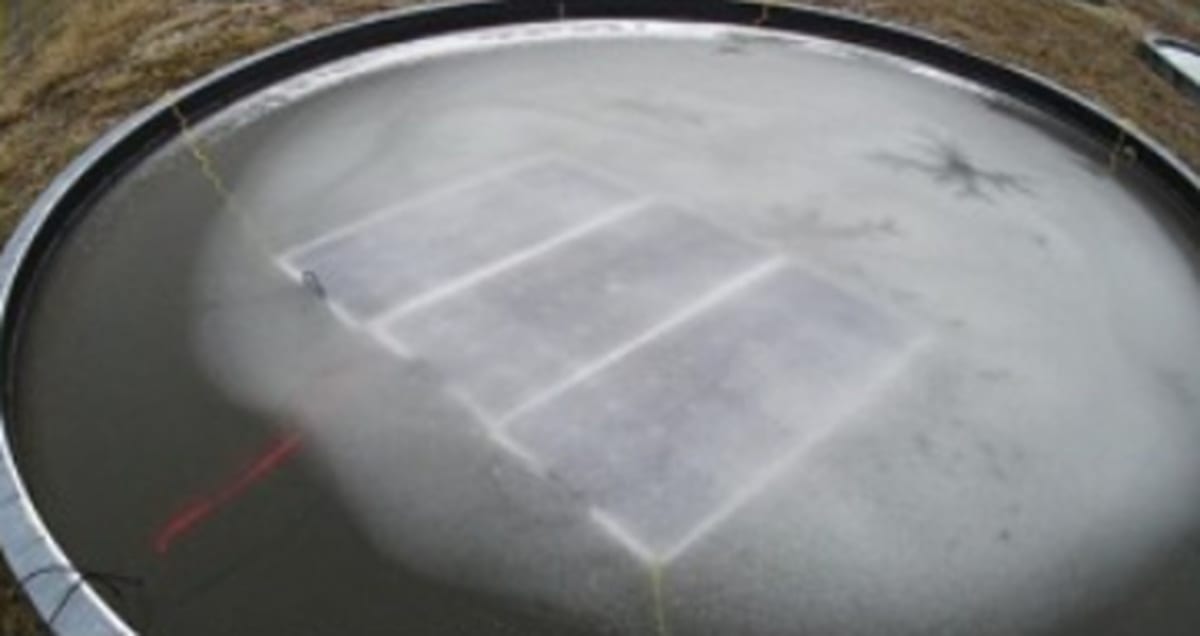 Solar panels floating on foam slabs across a Canadian pond with air-bubbler system