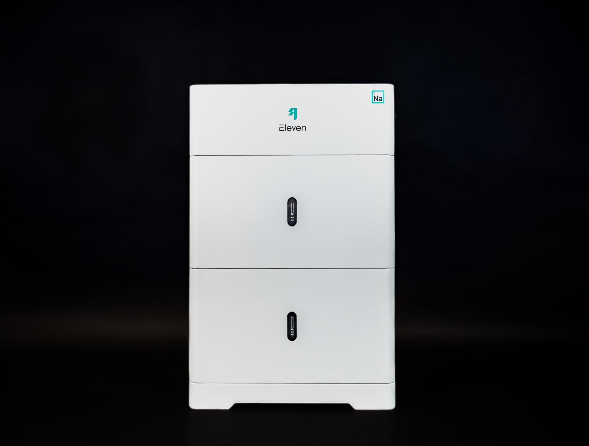 Modern white battery storage unit installed next to solar panels on residential home