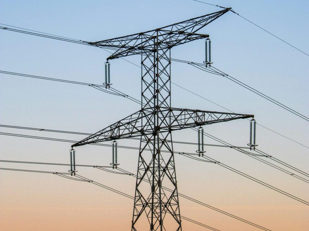 Solar panels and electrical transmission towers against blue sky in French countryside