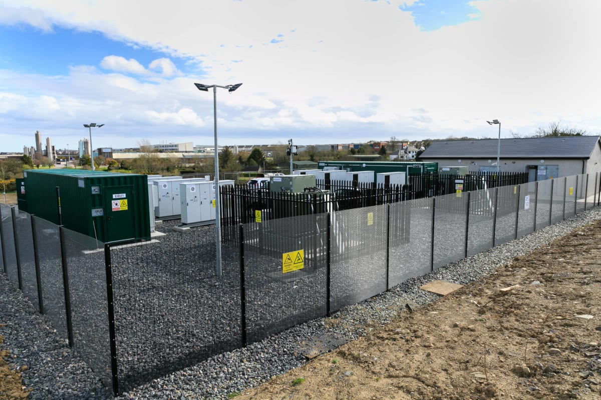 Large-scale battery storage facility with rows of battery units beside solar panels in Europe