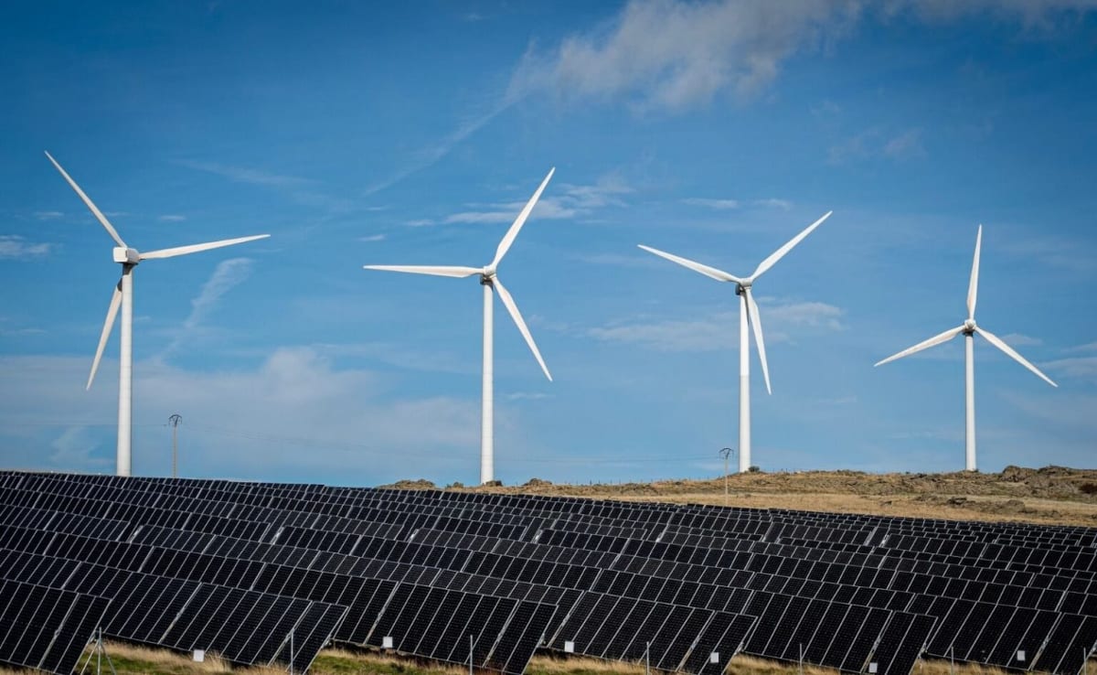 Rows of solar panels stretching across European countryside under bright blue sunny sky