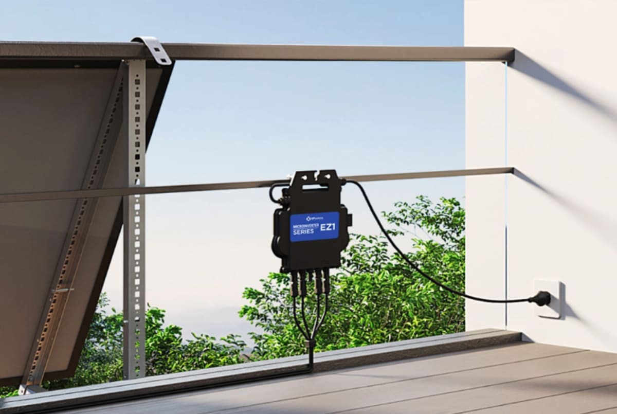 Solar panels mounted on apartment balcony connected to compact microinverter device with standard electrical plug